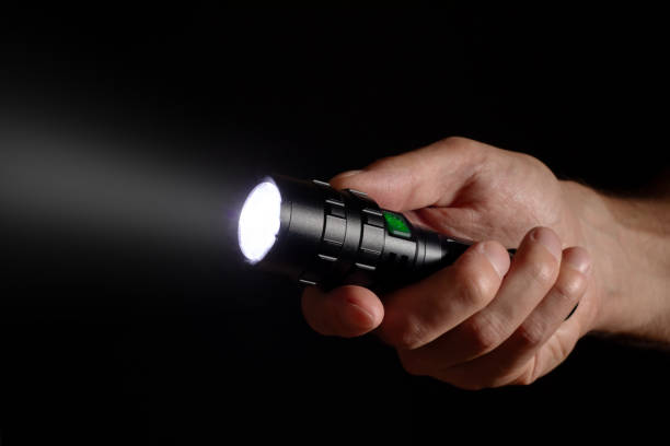 istock Male hand holding a led flashlight with a wide white beam on a black background, leaving the right side of the frame 1804121735
