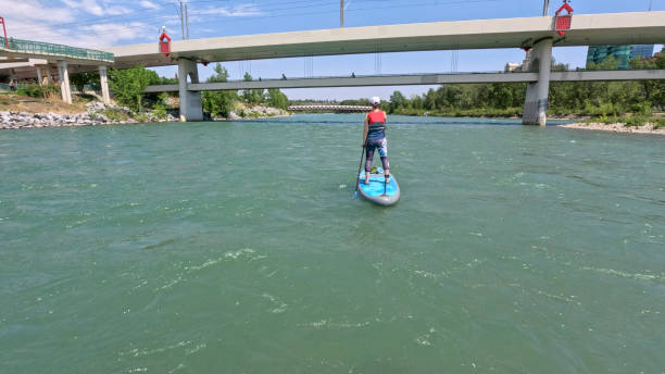Woman paddle boarding (SUP) towards bridges