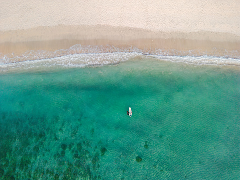 Directly above shot of woman with surfboard getting to line up on Bali