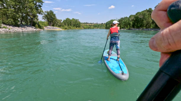 istock POV of woman paddle boarding (SUP) down river 1804137368