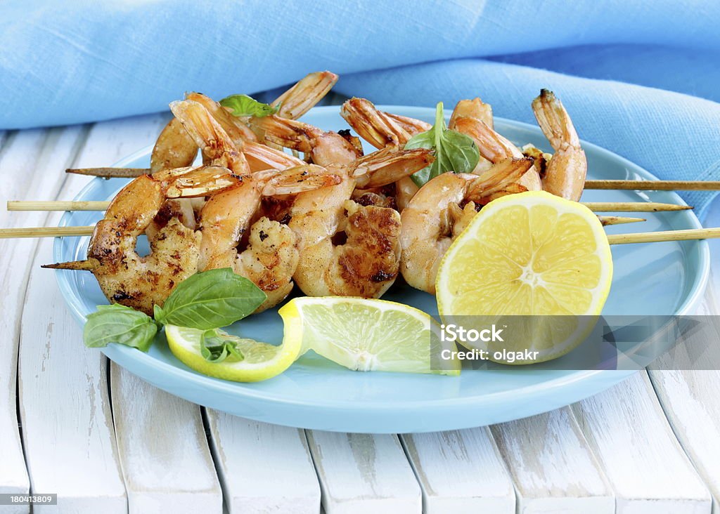 Spiedini di gamberi alla griglia su legno con limone e basilico - Foto stock royalty-free di Alla griglia