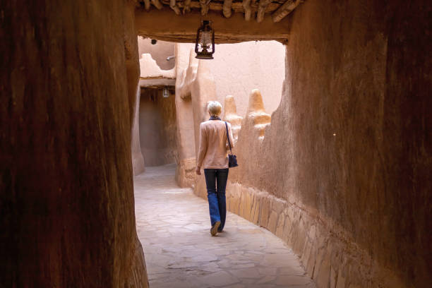 одинокая западная туристка, прогуливающаяся по узкой улочкам в деревне наследия ушайкер - arabia architecture asia rear view стоковые фото и изображения