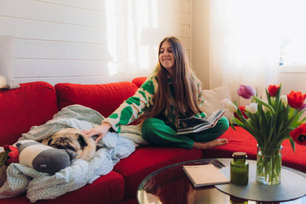 istock Woman Relaxing on Red Sofa with Her Dog Enjoying Reading 1804164549
