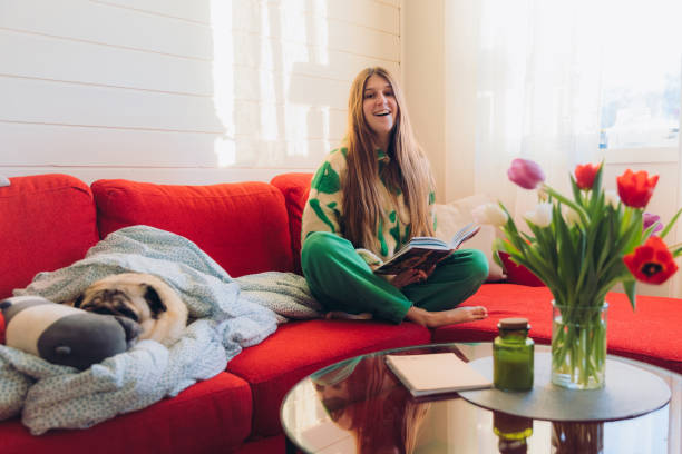 istock Woman Relaxing on Red Sofa with Her Dog Enjoying Reading 1804168178