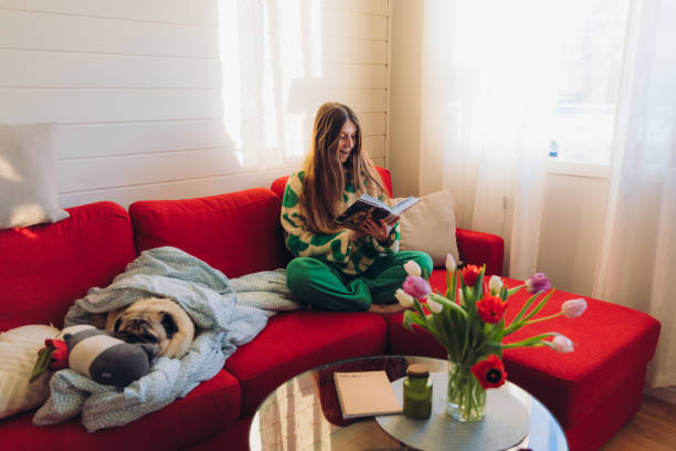 istock Woman Relaxing on Red Sofa with Her Dog Enjoying Reading 1804170827