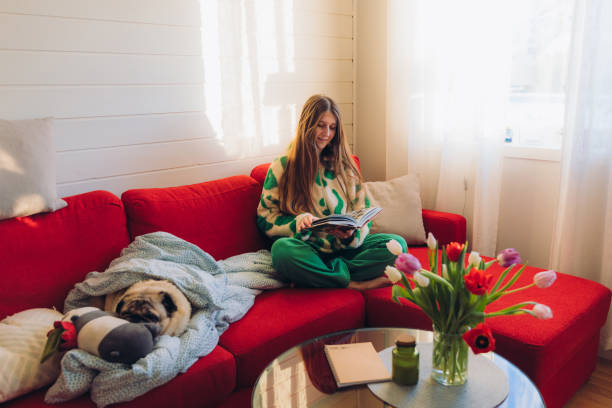 Woman Relaxing on Red Sofa with Her Dog Enjoying Reading