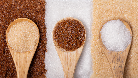 Various types of sugar in bamboo spoons, wholemeal, white and liquorice flavoured