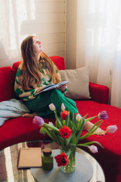 istock Woman Relaxing on Red Sofa with Her Dog Enjoying Reading 1804177790