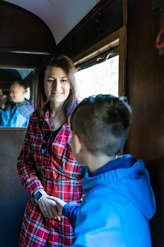 Mother and son riding a historic narrow track train. Family is ready for an adventure of a lifetime. Train travel on a sunny autumn day.