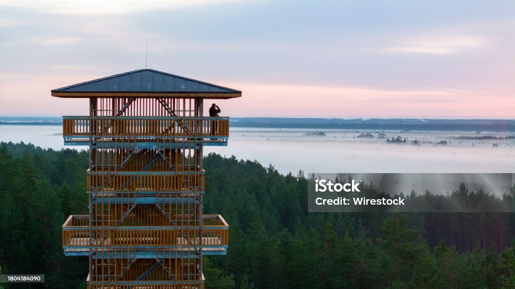 Sunrise on the watchtower in Rannamesta, Luitemaa Man is standing on the top balcony of the public Rannametsa-Tolkuse nature trail watchtower and observing with the binocular the sunrise bog lanscape Estonia Stock Photo