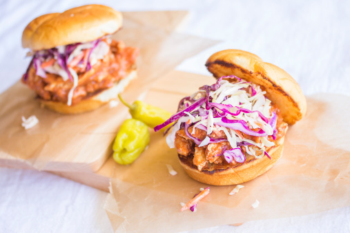 Shredded barbeque chicken topped with a tangy colorful slaw on a toasted sweet Hawaiian bread bun