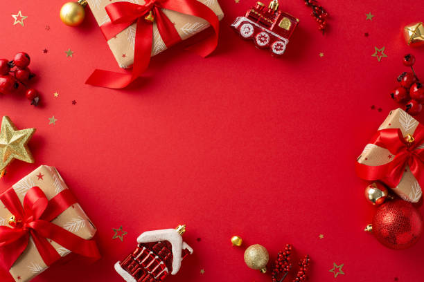 crafting holiday joy. top-down view of craft paper gift boxes decked out with red and gold decorations, mistletoe berries, confetti, against a cheerful red setting with frame for your festive message - decked imagens e fotografias de stock
