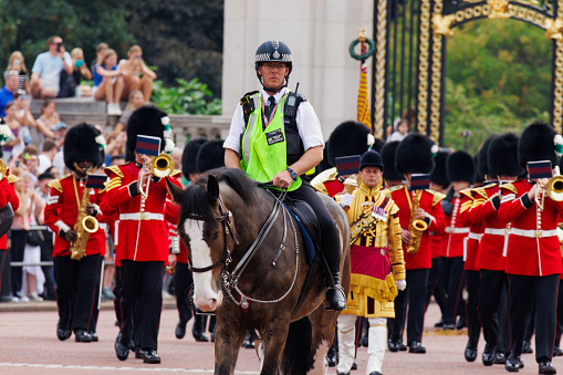 Police officer on horseback escorts the royal guard band during changing of the guard ceremony at Buckingham palace