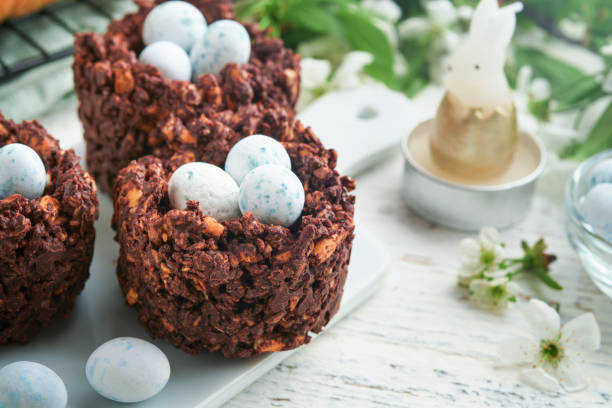 istock Easter brunch or breakfast. Easter chocolate nest cake with chocolate candy eggs, traditional hot cross buns and deviled eggs with bouquets of blooming apple trees. Spring Easter holiday food concept. 1804207214