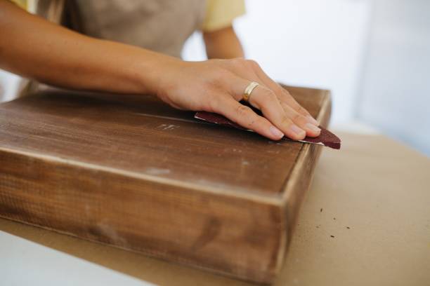 craftswoman sanding a wooden surface, close-up stock photo