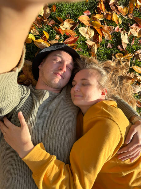 istock Couple lying in autumn leaves and taking selfie. 1804236446