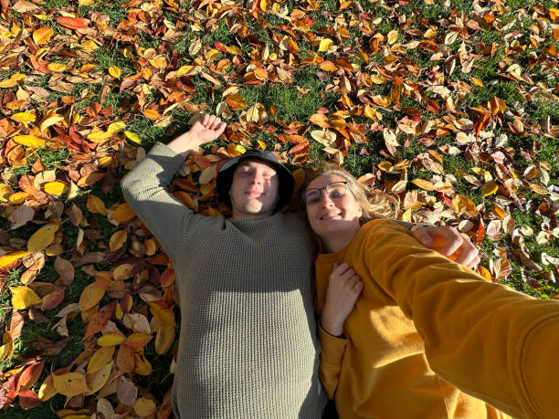 istock Couple lying in autumn leaves and taking selfie. 1804236982