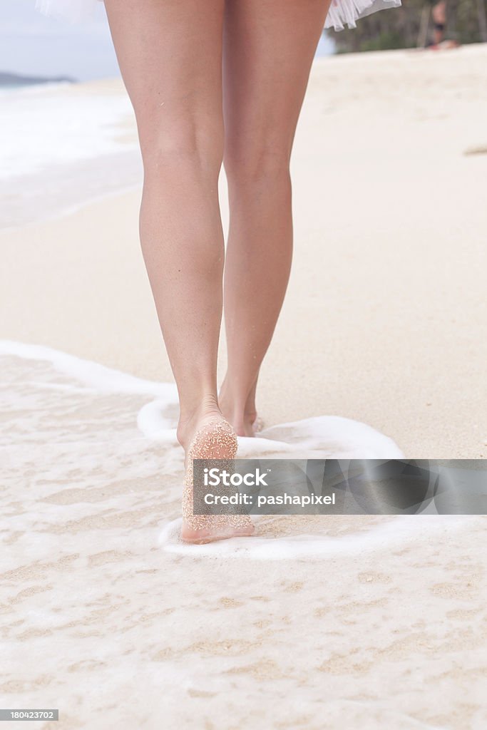 Donna che cammina lungo la sabbia sulla spiaggia - Foto stock royalty-free di Abbronzatura