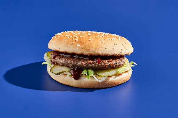 istock Beef burger blue background with hard shadow. American junk food minimal style. Hamburger trendy style.  Simple burger colour background. 1804239343