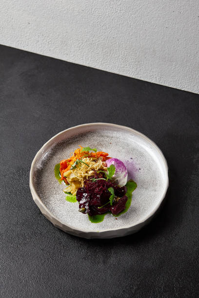 istock Baked root vegetables in handmade ceramic dishware. Vegan food - caramelized carrot, beetroot and celery on modern crockery. Vegetarian food innovative recipes 1804239670