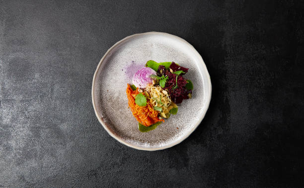 Baked root vegetables in handmade ceramic dishware. Vegan food - caramelized carrot, beetroot and celery on modern crockery. Vegetarian food innovative recipes