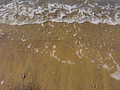 Sea waves coming to an empty beach on a sunny day. No people.