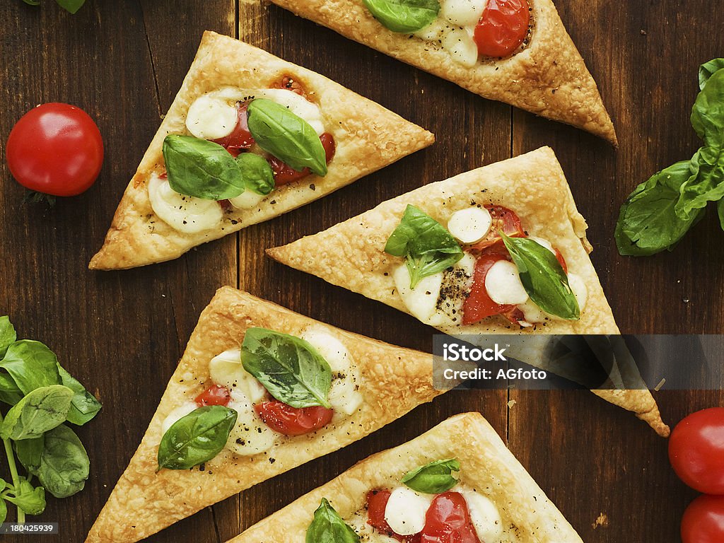 Puff-pizzas Puff-pizzas with mozzarella cheese, cherry tomatoes and baby basil. Viewed from above. Appetizer Stock Photo
