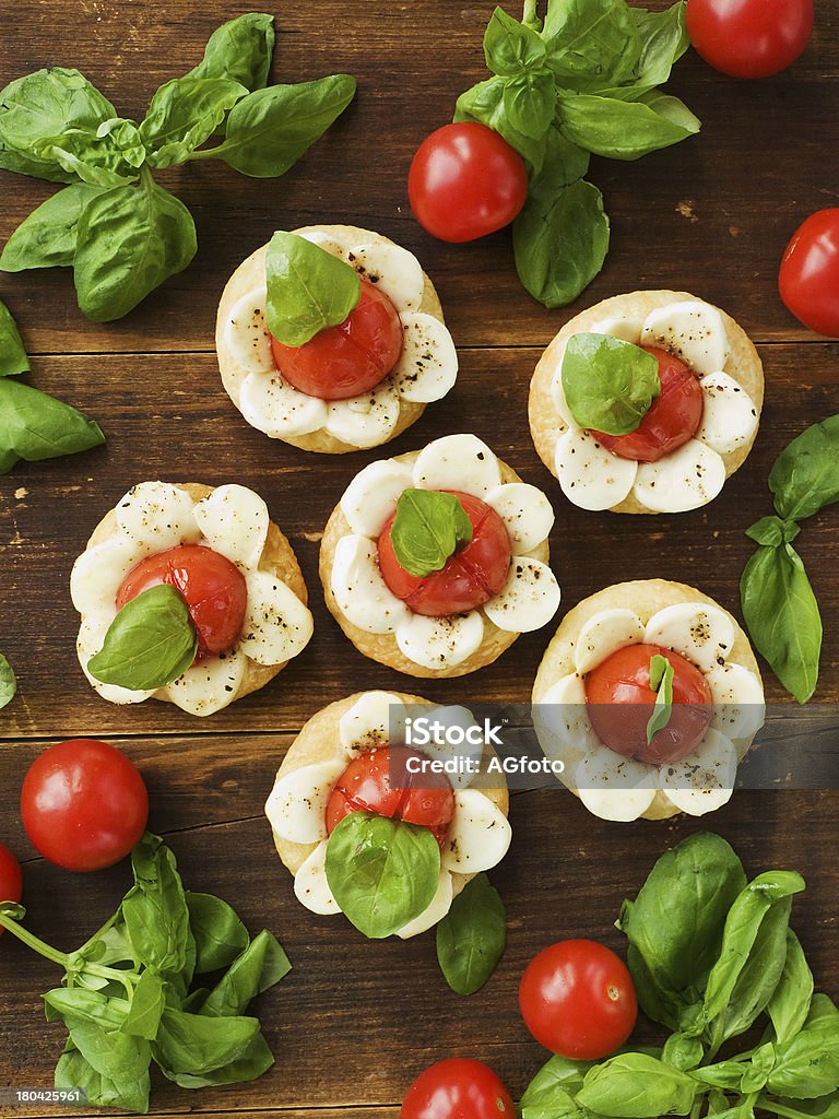 Puff-pizzas Puff-pizzas with mozzarella cheese, cherry tomatoes and baby basil. Viewed from above. Appetizer Stock Photo