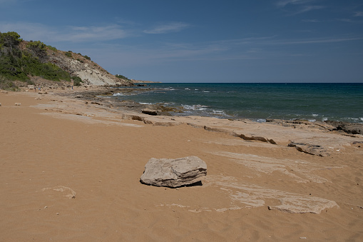 Red sandy beach with large stone in Calabria, Italy
