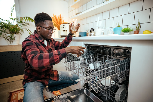 Man uses a dishwasher in the kitchen