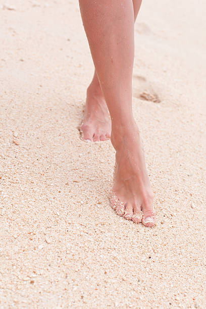 istock Woman walking through sand on the beach 180427929