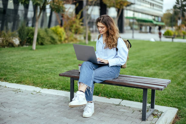 istock Young woman uses a laptop outdoors 1804281149