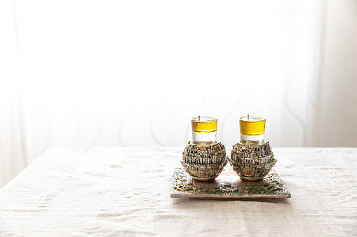 A pair of a special Shabbat candlesticks with the city of Jerusalem engraved on them with oil on the Shabbat table.