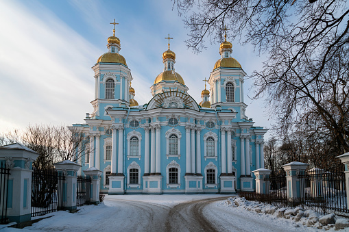 View of the Tobolsk Kremlin (Siberia, Russia) in winter. Old white stone churches with gold and blue domes, a multi-tiered bell tower against the background of the blue morning sky.