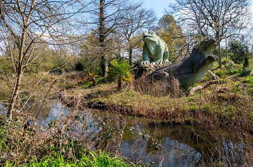 Two Iguanodon dinosaur sculptures on an island in the public Crystal Palace Park in South East London. The dinosaurs were constructed in the park in 1854 when the former 1851 Great Exhibition glass ‘palace’ was moved to Sydenham after the exhibition closed. The new, extensive pleasure gardens contained a collection of around 30 ‘dinosaurs’ and other extinct creatures, which are now known to be anatomically inaccurate. They are, however, a famous and much-loved attraction in South East London. The sculptures were created by one of the 19th-century’s best-known natural history sculptors, Benjamin Waterhouse Hawkins (1807-1894). The landscape in which they are set was designed by Joseph Paxton, designer of the Crystal Palace glass building.