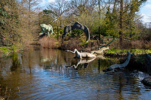 Some of the famous Plesiosaur, Ichthyosaur and Teleosaurus dinosaur sculptures in the public Crystal Palace Park in South East London. The dinosaurs were constructed in the park in 1854 when the former 1851 Great Exhibition glass ‘palace’ was moved to Sydenham after the exhibition closed. The new, extensive pleasure gardens contained a collection of around 30 ‘dinosaurs’ and other extinct creatures, which are now known to be anatomically inaccurate. They are, however, a famous and much-loved attraction in South East London. The sculptures were created by one of the 19th-century’s best-known natural history sculptors, Benjamin Waterhouse Hawkins (1807-1894). The landscape in which they are set was designed by Joseph Paxton, designer of the Crystal Palace glass building.