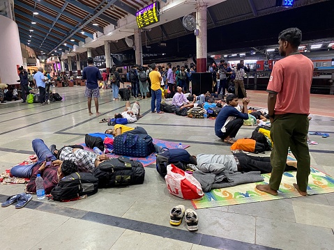Margao, Goa, India - October 10 2023: Passengers sleeping on the floor of a railway station while waiting for a train.