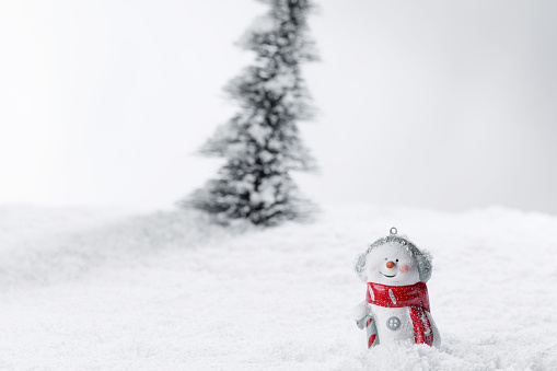 Miniature decorative Christmas tree and snowman placed on snow