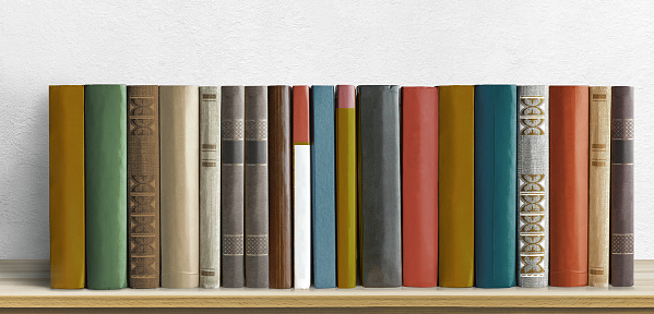 Old books on a wooden shelf on white textured wall