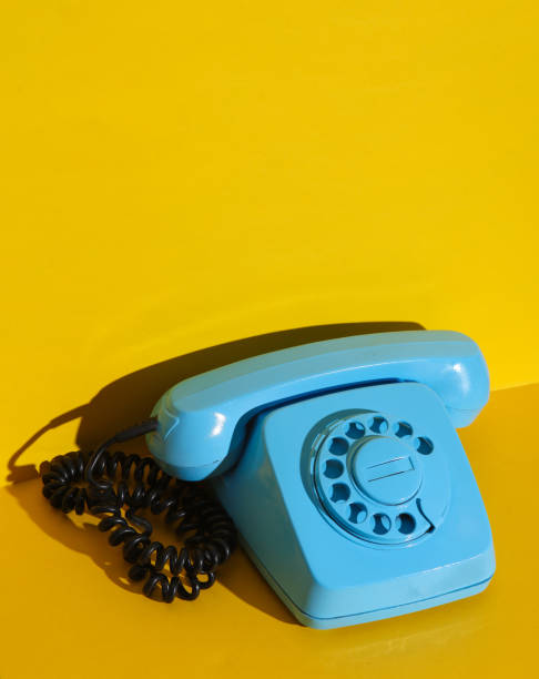 istock Rotary retro rotary telephone painted in blue paint on a yellow wall background. Creative layout 1804340122