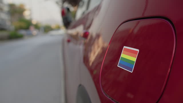 Applying Pride Sticker to Red Car