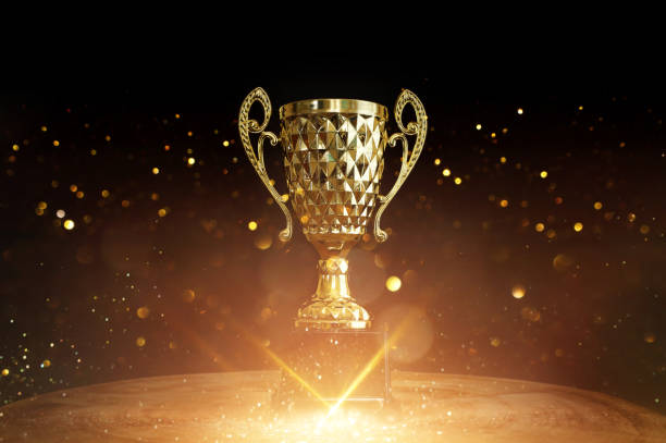 istock Image of trophy over wooden table and dark background, with abstract shiny lights 1804345607