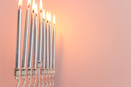 Photo of menorah with nine burning candles in dark. No people are seen in frame. Shot with a full frame mirrorless camera.