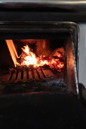 Small fire in an old stove in a countryside home in Finland, Northern Europe. Closeup image of fire, cooking.
