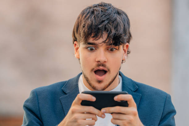 istock young male with mobile phone and surprised face 1804401202