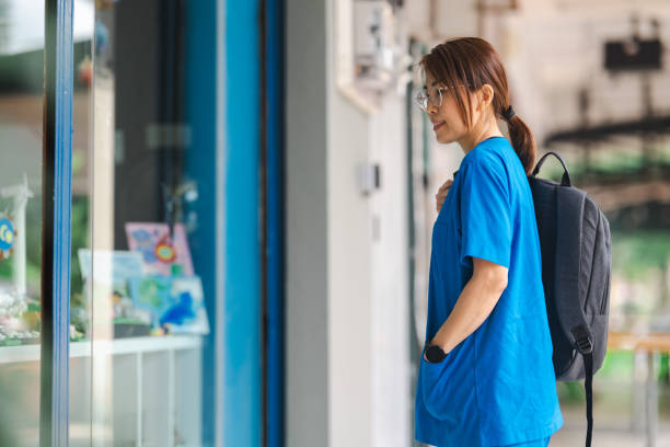 istock Reflective Moment: Asian Chinese Nurse Contemplates by Mall Window 1804401219