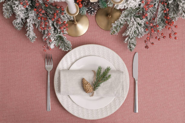 istock Festive place setting with beautiful dishware, cutlery and cone for Christmas dinner on pink tablecloth, flat lay 1804408311