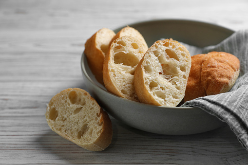 Fresh crispy ciabattas on white wooden table. Space for text