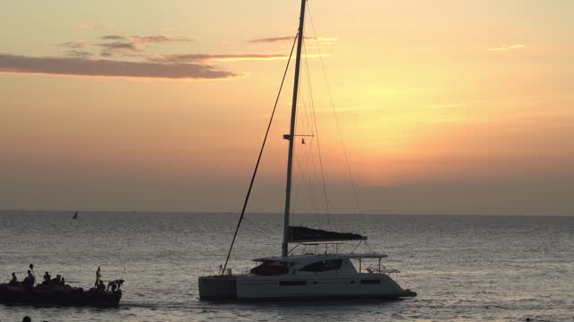 silhouetted moored catamaran at sunset with sunlight