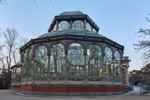 Victorian glass pavilion in a park at dusk, reflecting the twilight light.